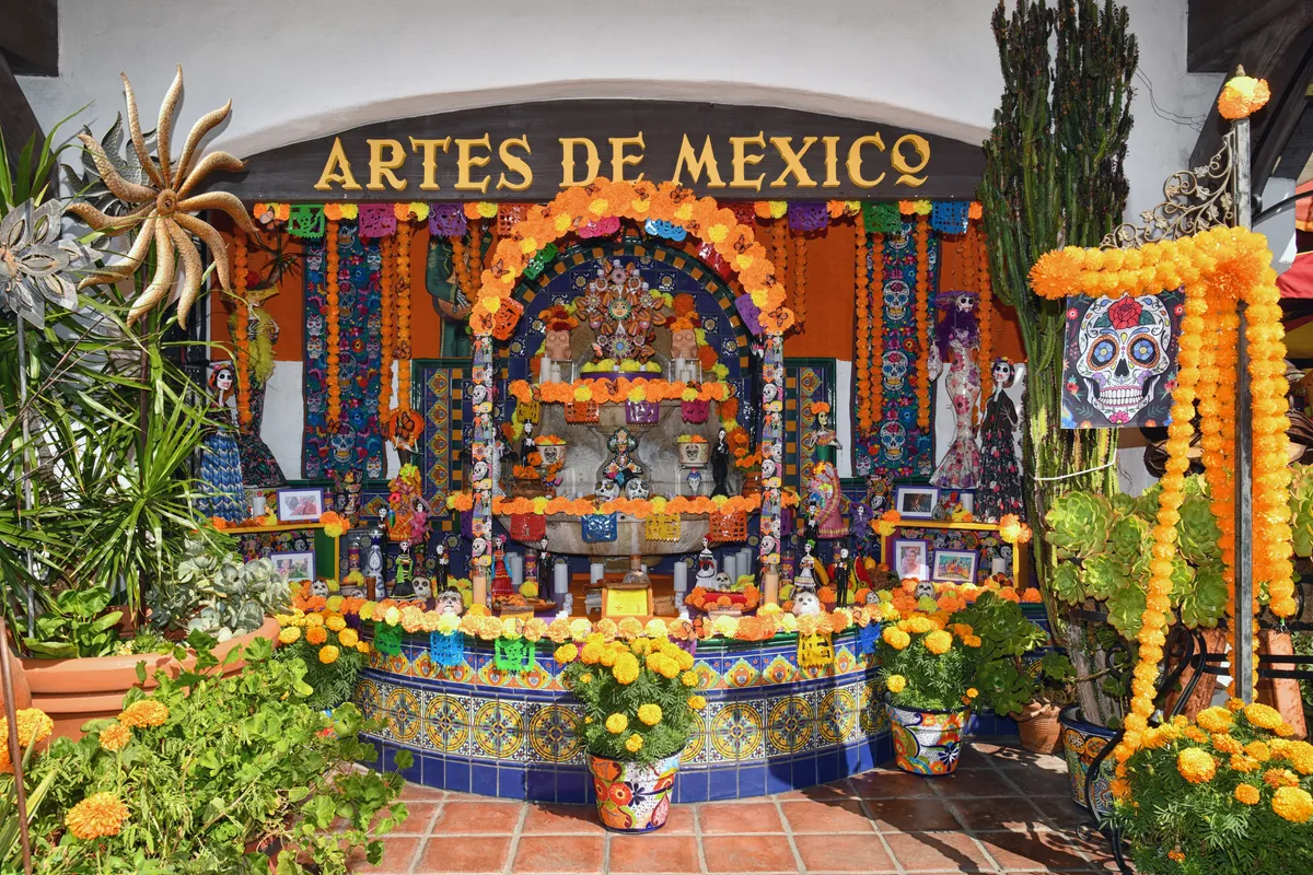 Sunlit courtyard and storefront of Bazaar del Mundo Shops in Old Town San Diego, framed by blooming bougainvillea