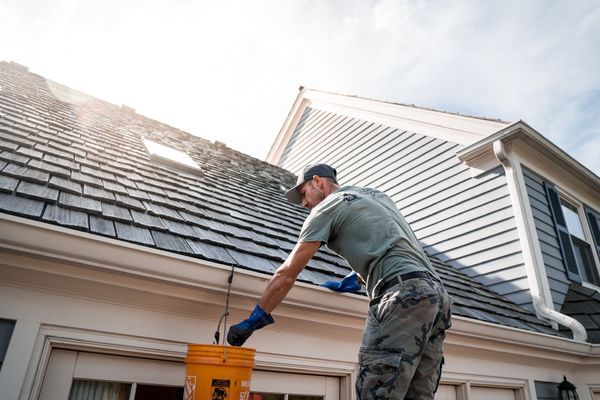 Professional cleaning gutters on a house roof in spring to prevent water damage and clogs