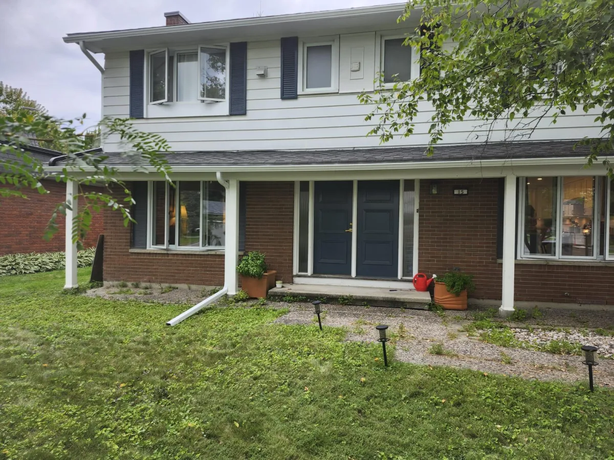 Exterior of a suburban home displaying a white eavestrough system and downspout extending onto the front lawn.