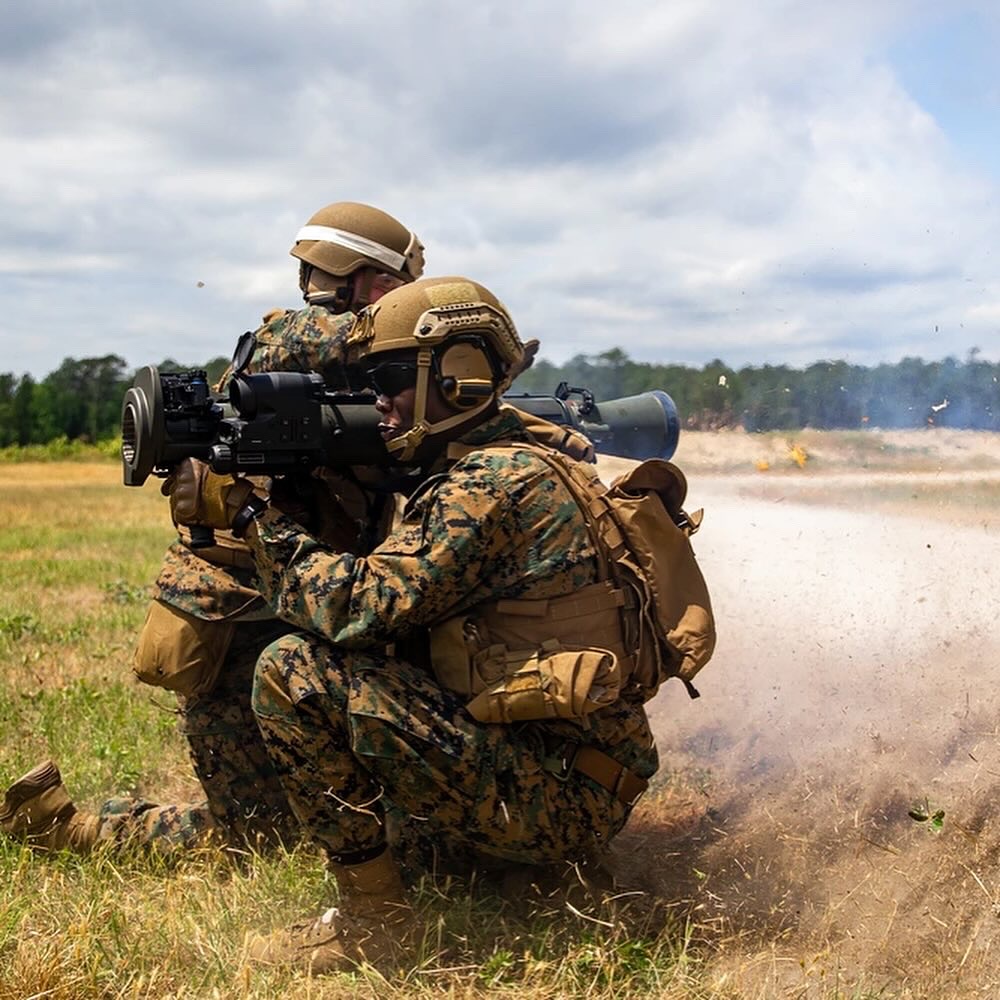 soldier crouching in a field aiming a rocket launcher