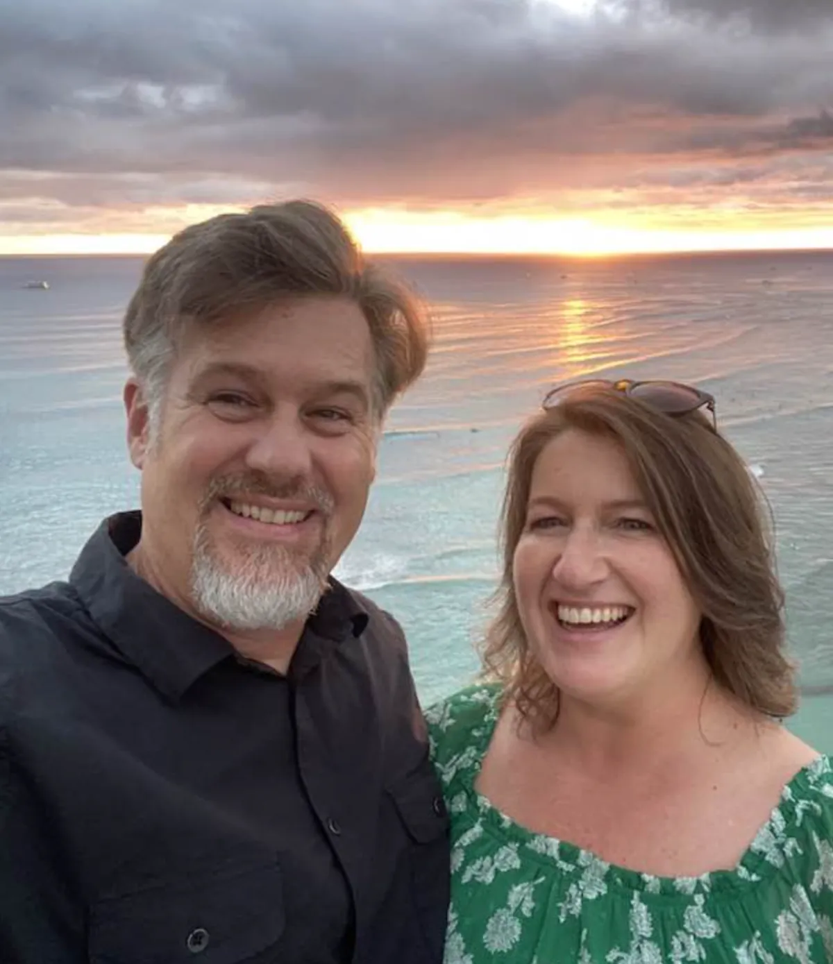 Smiling couple posing outdoors on a scenic wooded trail, dressed in smart casual attire, symbolizing partnership, success, and a balanced lifestyle.