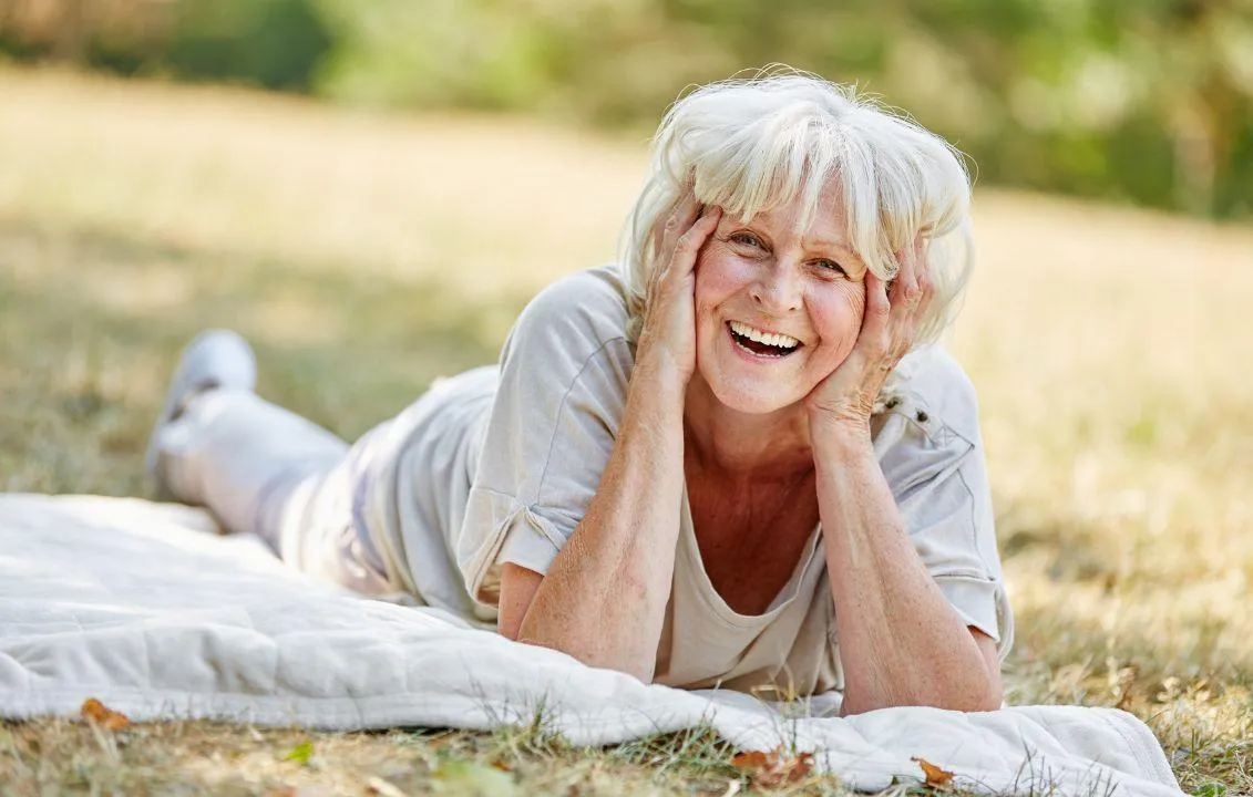 old lady lying flat on her stomach in a picnic setting