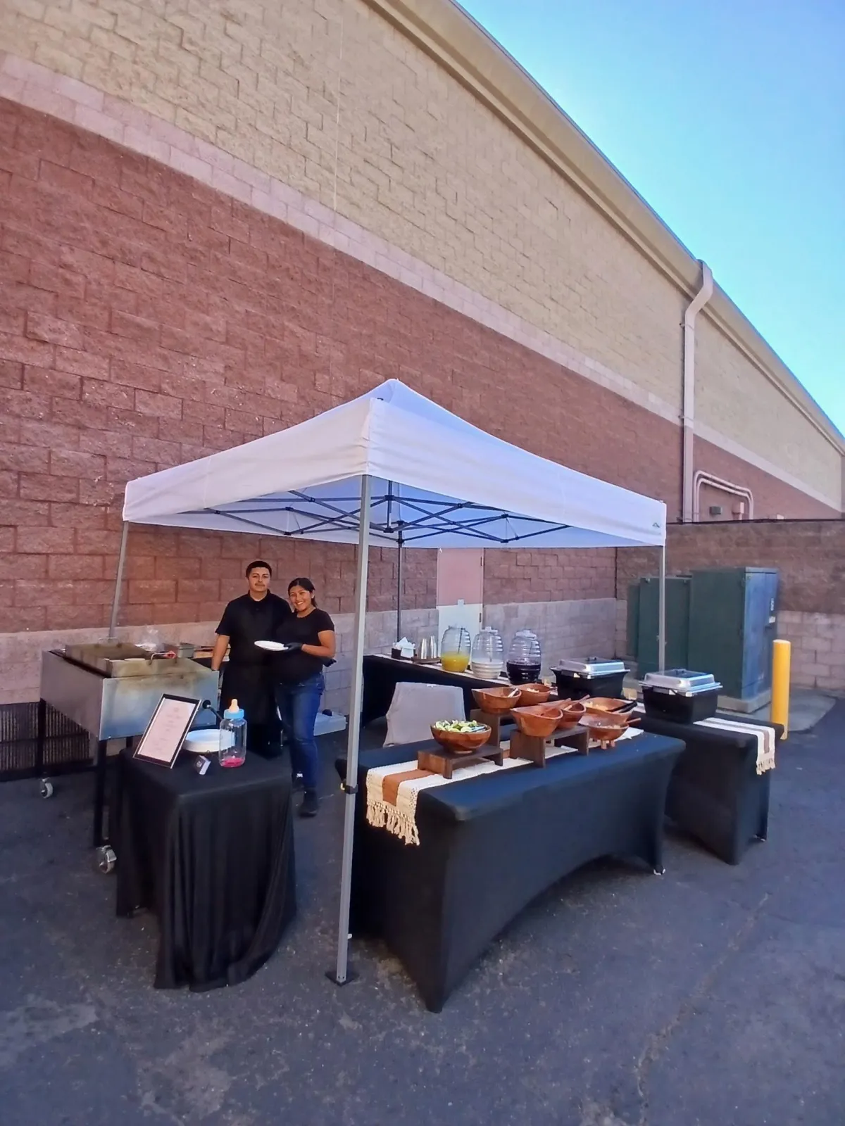 On-site taco catering setup with grill station, toppings bar, and aguas frescas drink station.