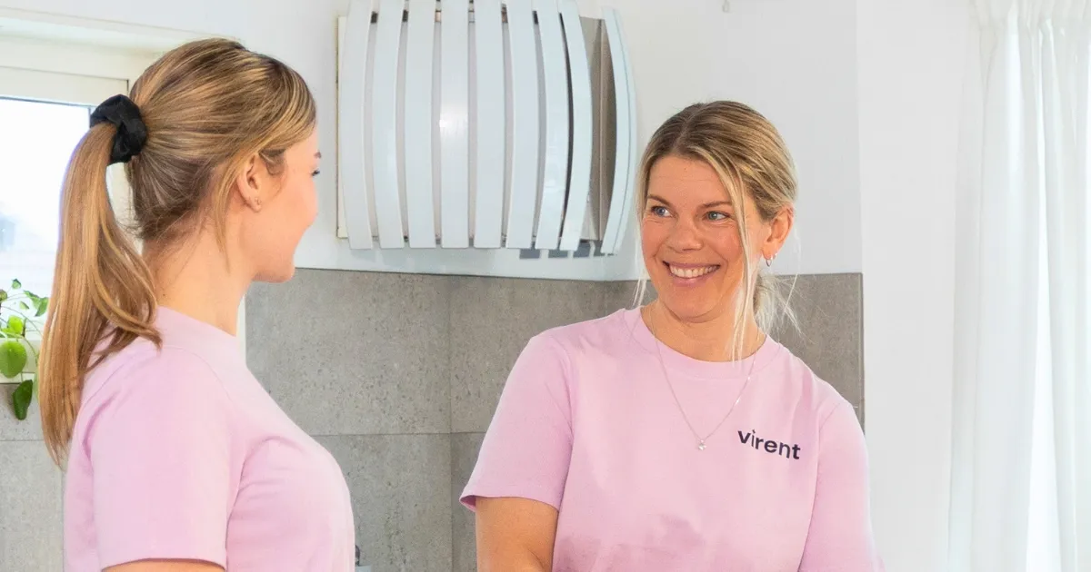 Två medarbetare från Virent i lila arbetskläder möts med ett leende i ett ljust kök.