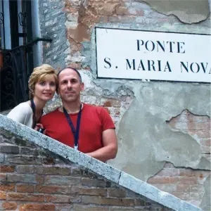 Couple standing on a brick staircase next to a sign that reads 'Ponte S. Maria Nova' in Italy