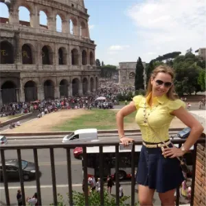 Woman in a yellow top posing in front of the Colosseum in Rome, Italy