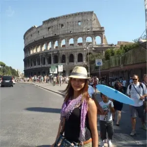 Woman posing in front of the Colosseum in Rome, Italy with tourists walking nearby