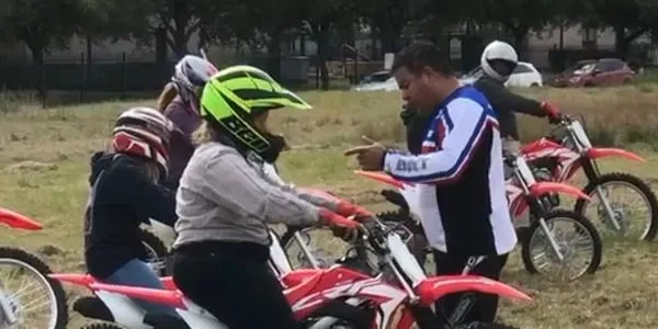 Motorcycle racer in full leathers leaning a bright red sportbike into a high-speed corner on a paved racetrack, wearing a yellow jersey and reflective visor during an October CMRA event.