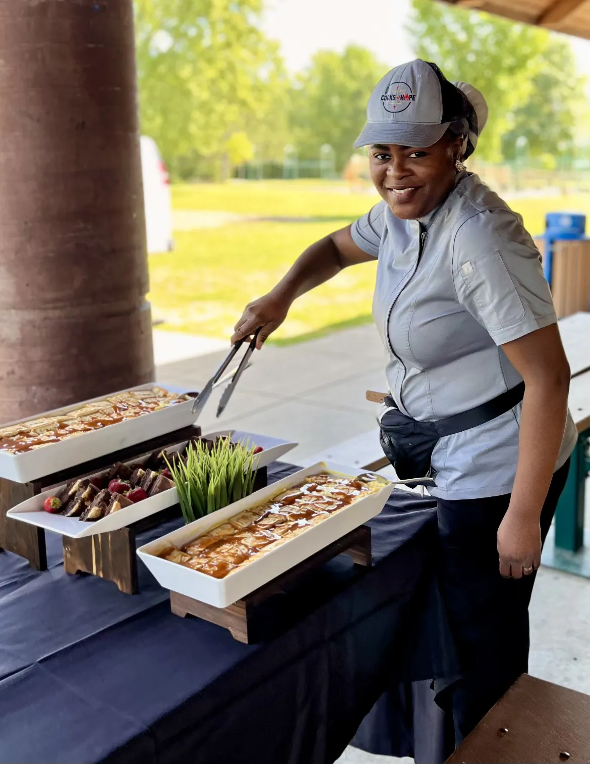 Peguy Johnson Founder Smiling as she serve food.