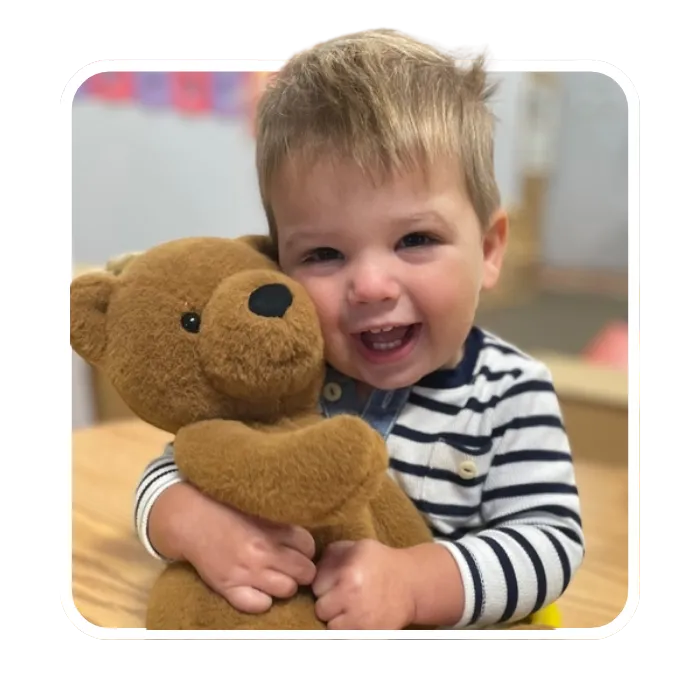 A child holding a teddy bear at Rosebrook Child Development Center, highlighting the nurturing and supportive environment for Michigan children.