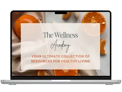Laptop displaying “The Wellness Academy” over a plate of colorful whole foods including vegetables, fruits, and grains.