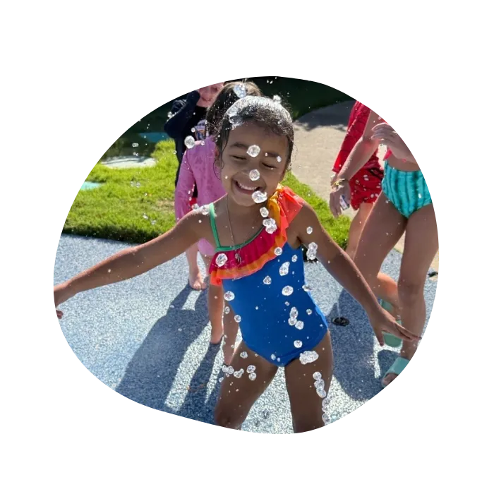 child having fun on splash pad outside