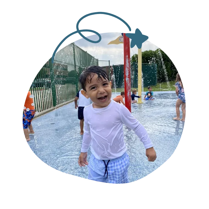 child playing outside in splash pad in daycare