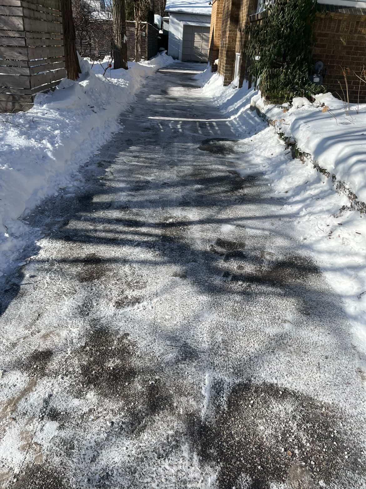 Technician shoveling a snowy sidewalk and front steps