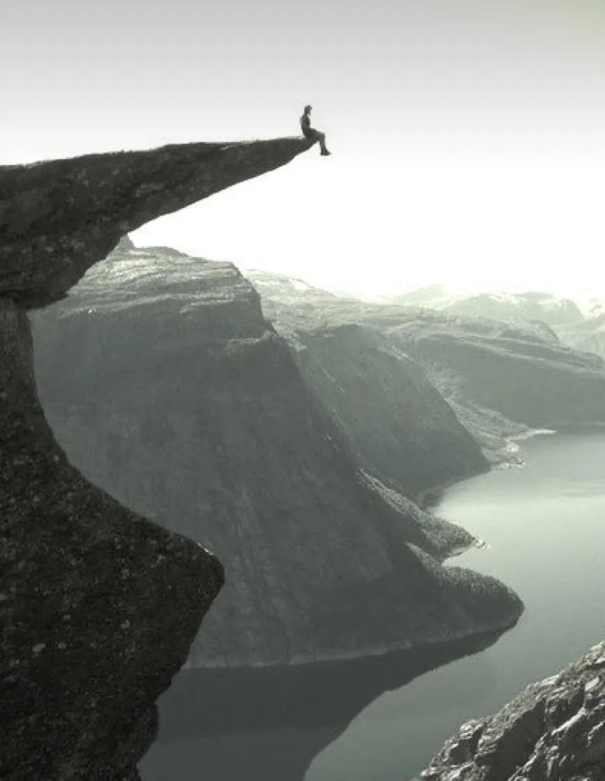 ein Person die auf einer klippe sitzt, der die Aussicht genießt 