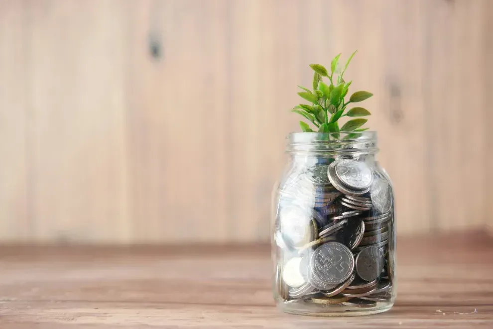Coin jar with a growing plant, symbolizing building a healthy money mindset