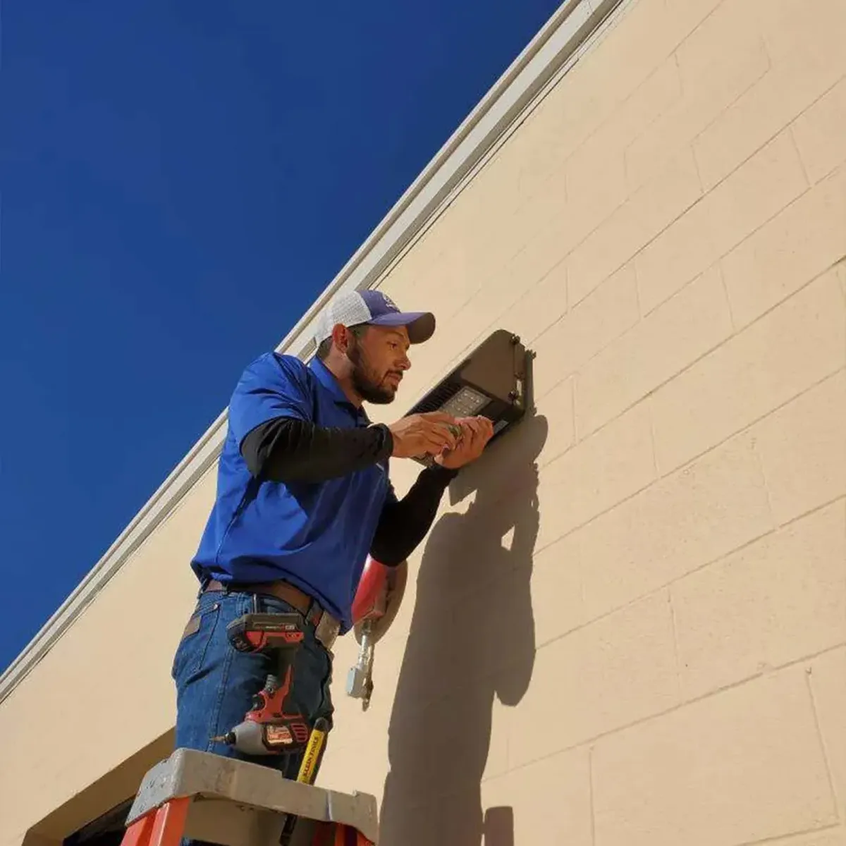 Licensed Caldwell Electrical technician installing residential electrical fixture on exterior wall for home upgrade in El Paso, TX