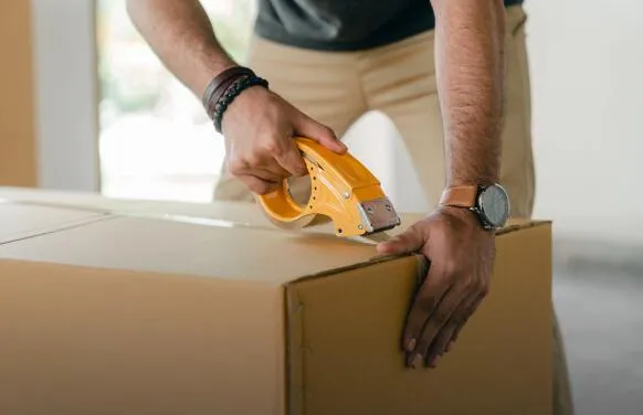 A person taping up a box moving house