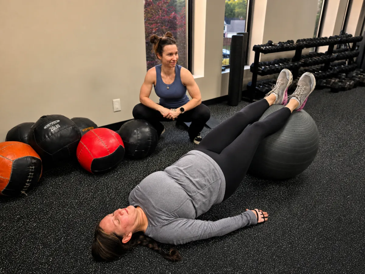 Personal trainer guiding client through stability ball exercise at 4Balance Fitness