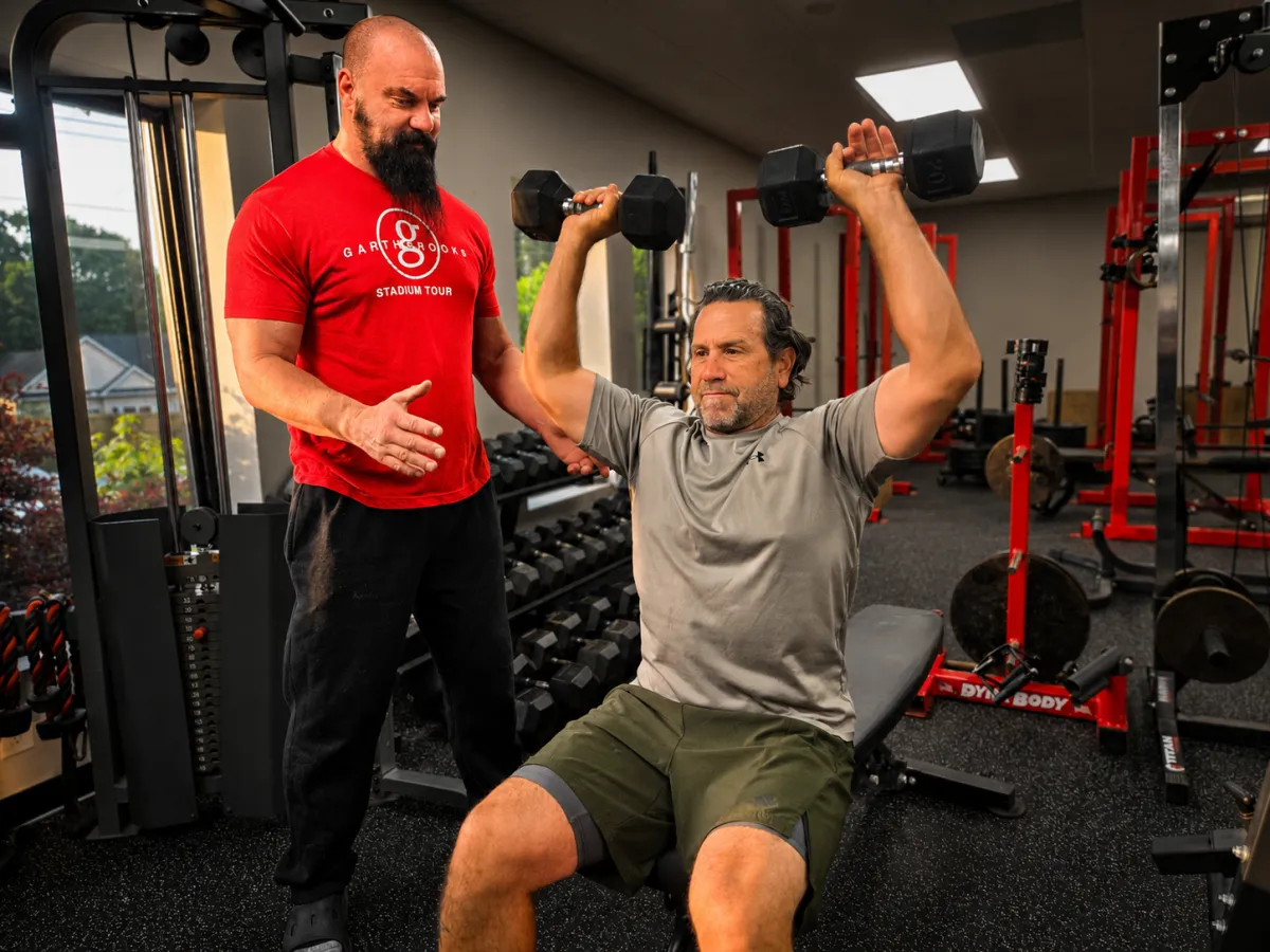 Personal trainer Michael Cole coaching client through dumbbell shoulder press at 4Balance Fitness