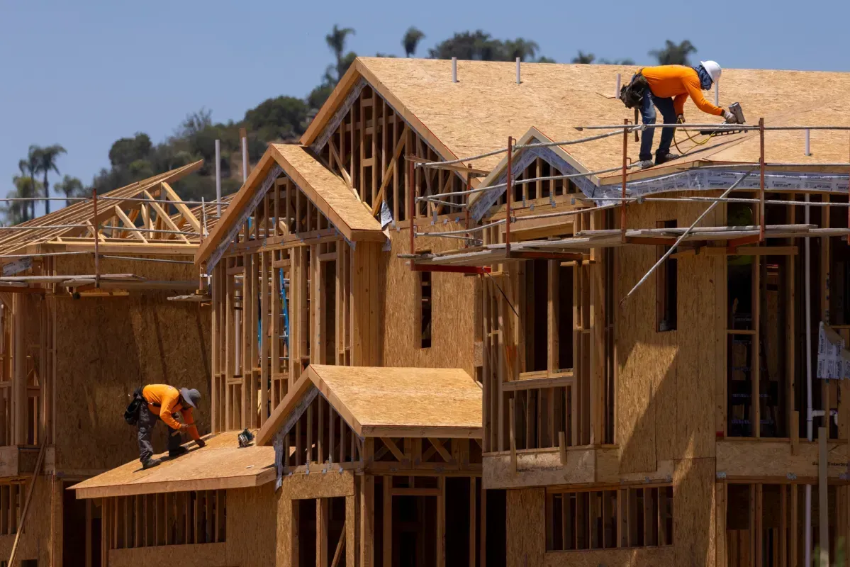 Construction crew nailing plywood during new home framing project.