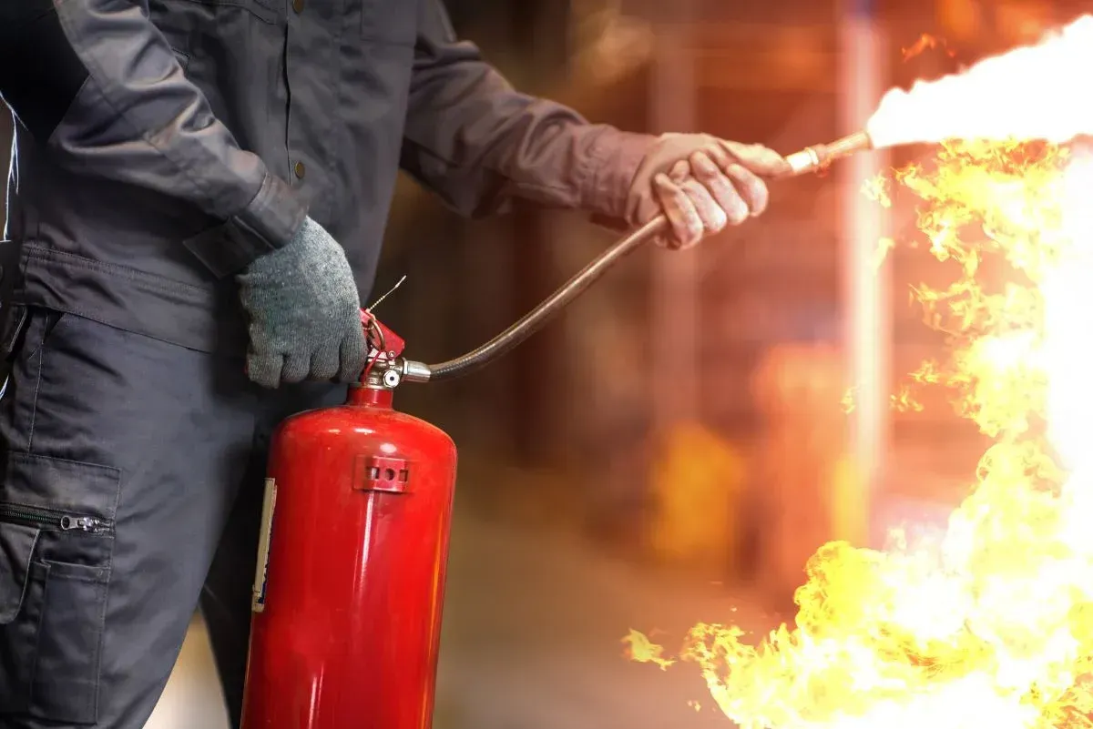 Individual using a fire extinguisher to put out a fire, highlighting the importance of VHrestoration's fire extinguisher cleanup services after fire incidents.