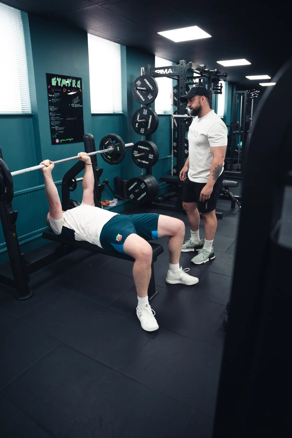 A man in a white shirt is standing in a gym