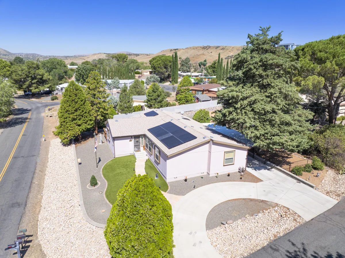 Aerial view of 1328 N Pinto Trail, Dewey-Humboldt AZ – home with solar panels, mountain views, landscaped yard, and driveway in golf community.
