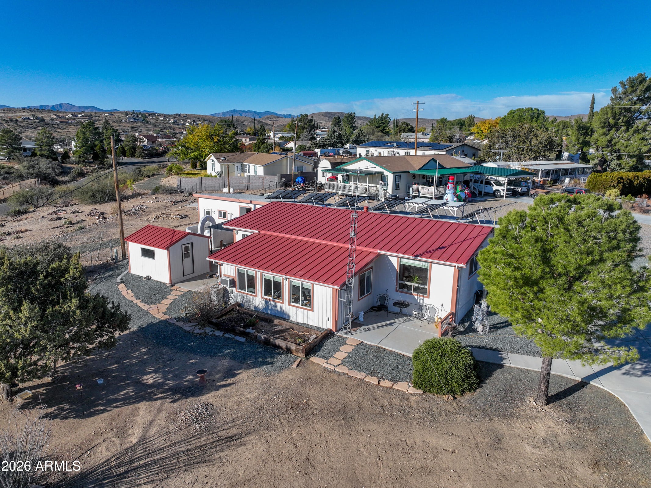 Aerial view of 1328 N Pinto Trail, Dewey-Humboldt AZ – home with solar panels, mountain views, landscaped yard, and driveway in golf community.