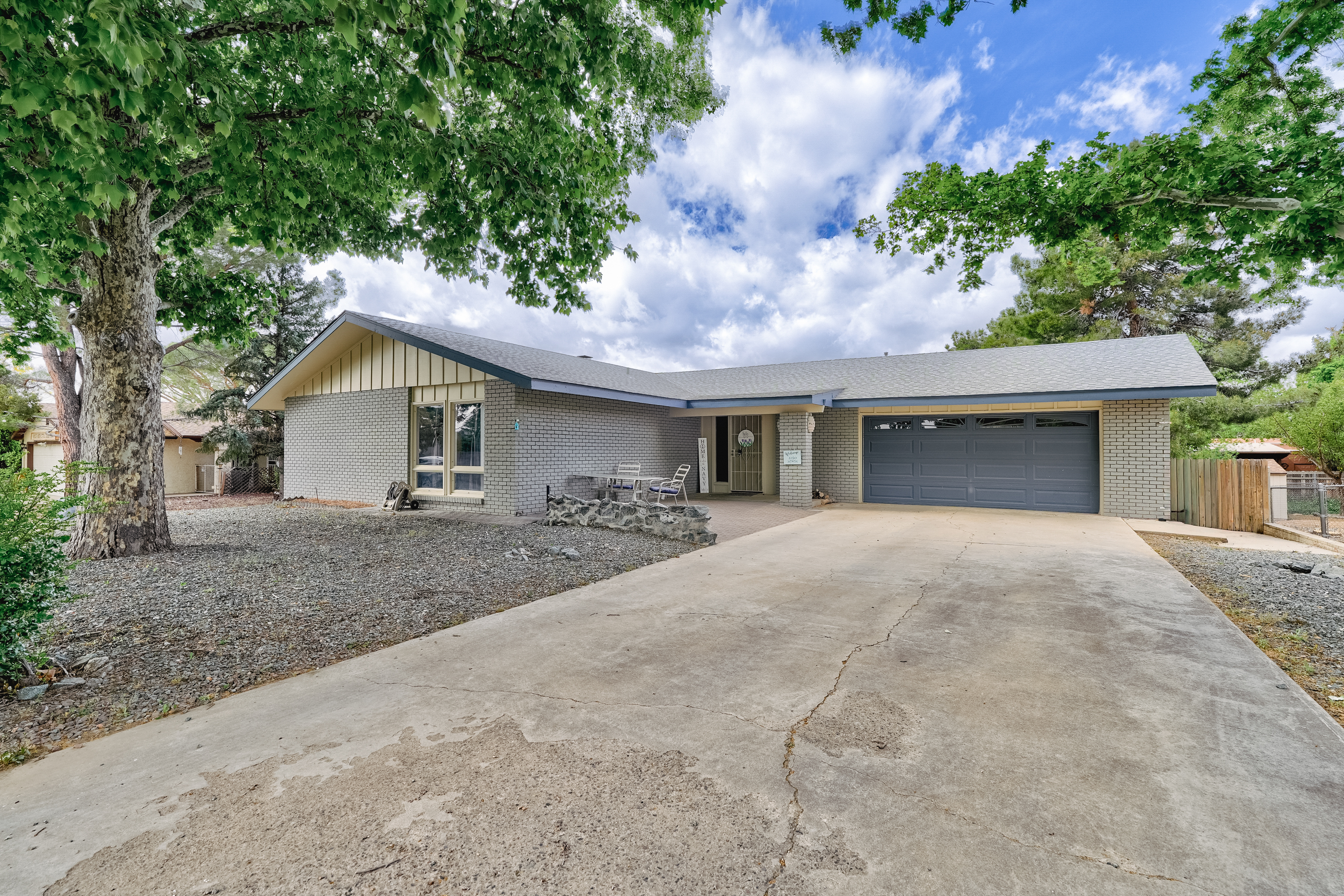 Aerial view of 1328 N Pinto Trail, Dewey-Humboldt AZ – home with solar panels, mountain views, landscaped yard, and driveway in golf community.