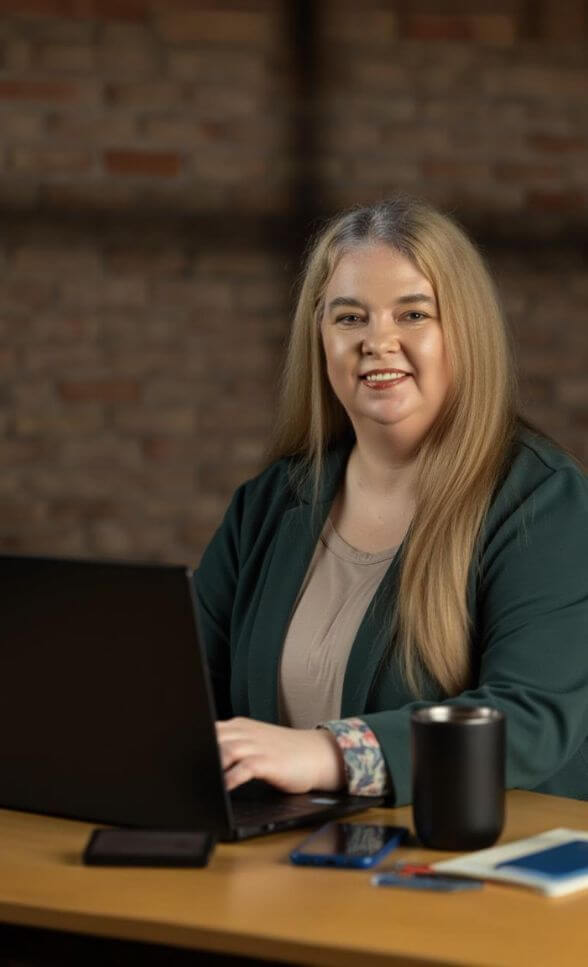 Lisa Leffler, founder of Fiscallytics, working on a laptop in a modern office — helping digital entrepreneurs clean up their books, streamline systems, and grow profit with confidence