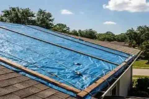 Blue emergency tarp secured over storm-damaged residential roof in Eden Prairie