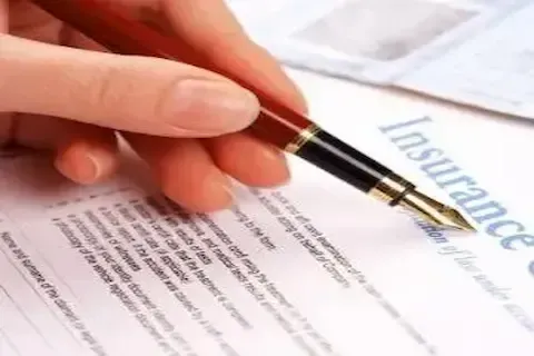 Hand signing roof insurance claim paperwork during adjuster documentation process