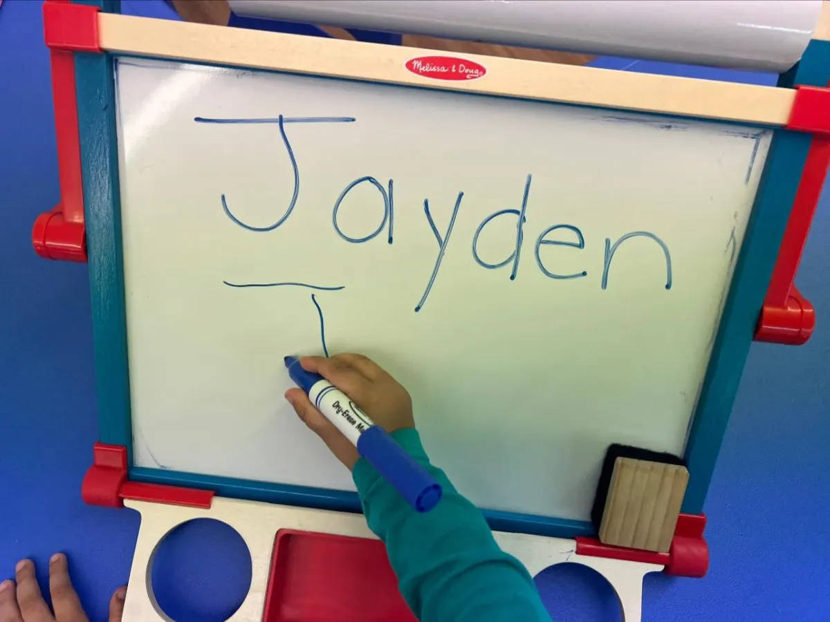 Girl stretches to the side while watching teacher on large screen TV