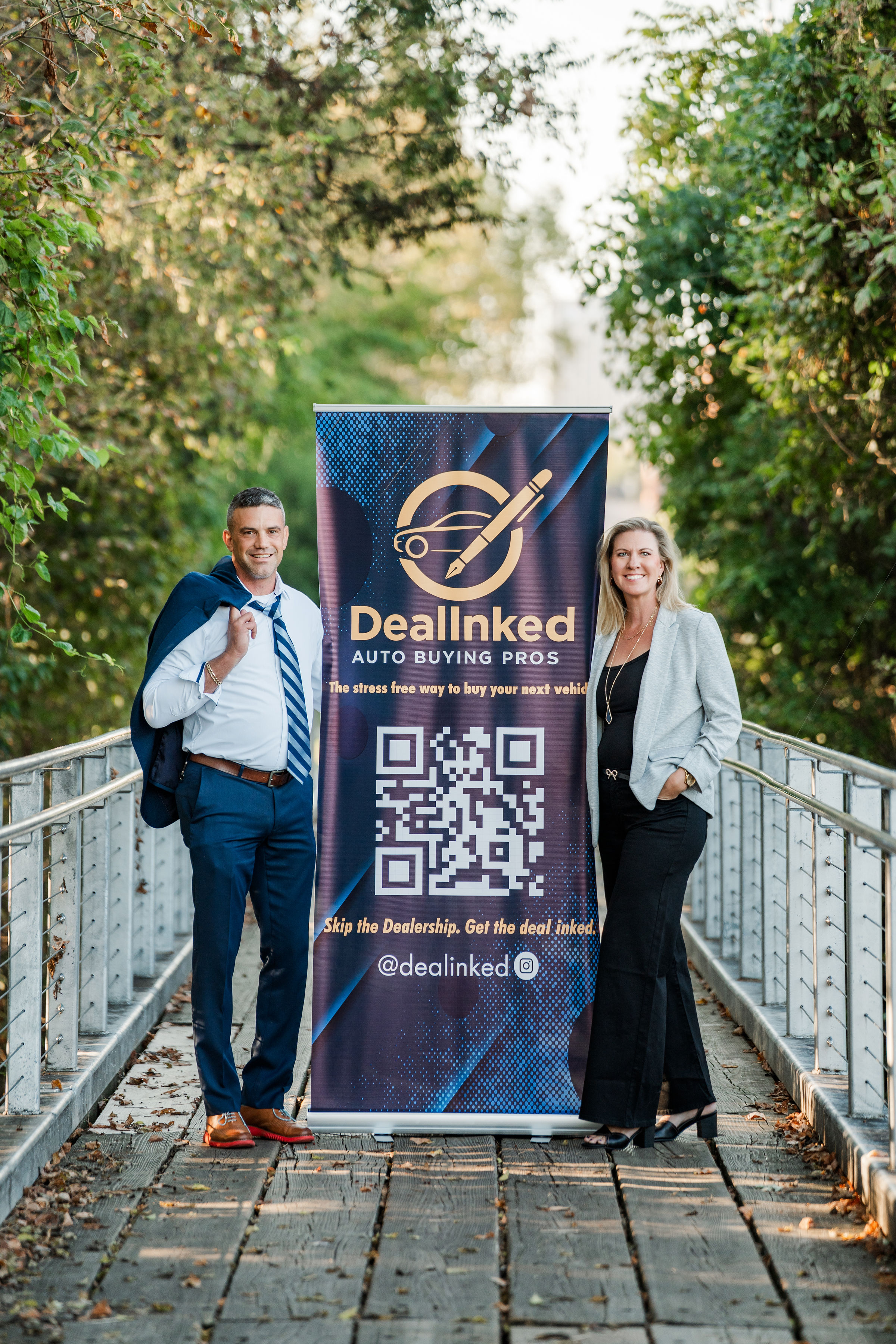 Two founders, a man and a woman, stand in front of a dealership window, smiling and shaking hands. Both wear business casual attire and exude confidence and approachability. The background shows a few cars and a bright, welcoming office.