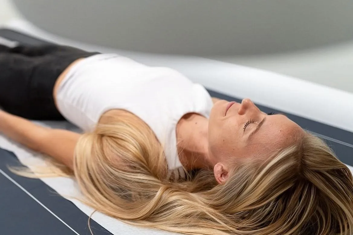 woman on a DEXA scan table undergoing  DEXA bone density scan at DexaFit