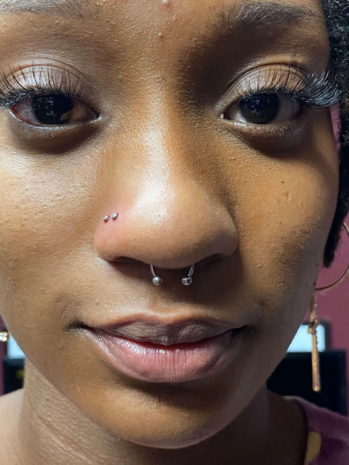 Close-up of a person with a septum piercing and two nostril piercings, showcasing professional body modification and aesthetic expression.