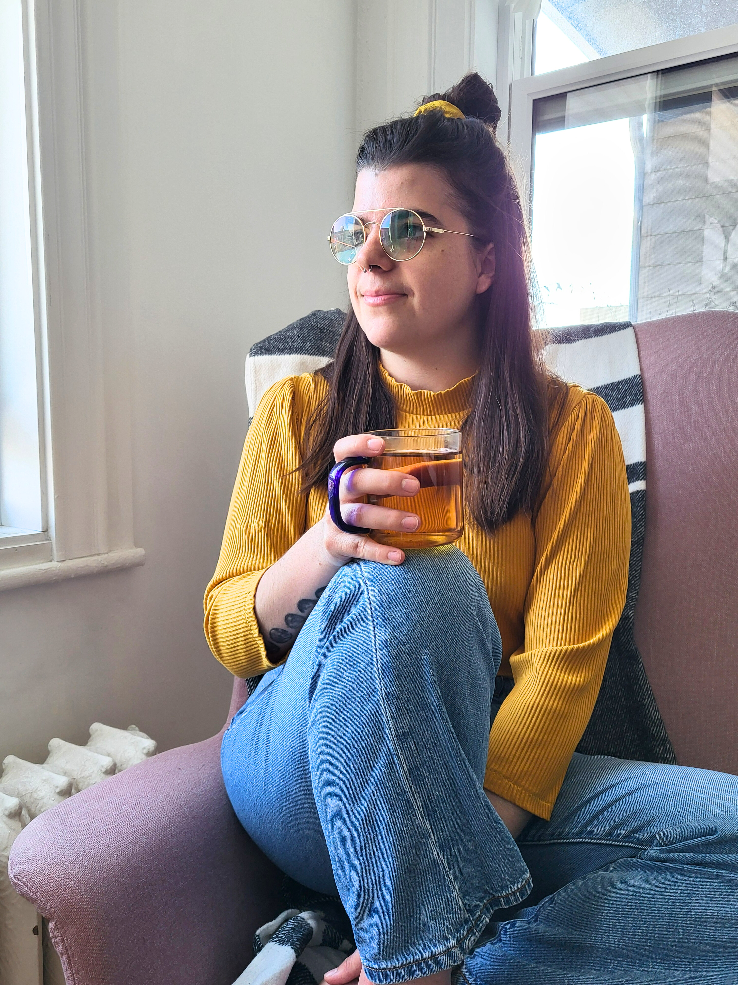 Catherine Perron, physiothérapeute, assise près d'une fenêtre avec une tasse de thé