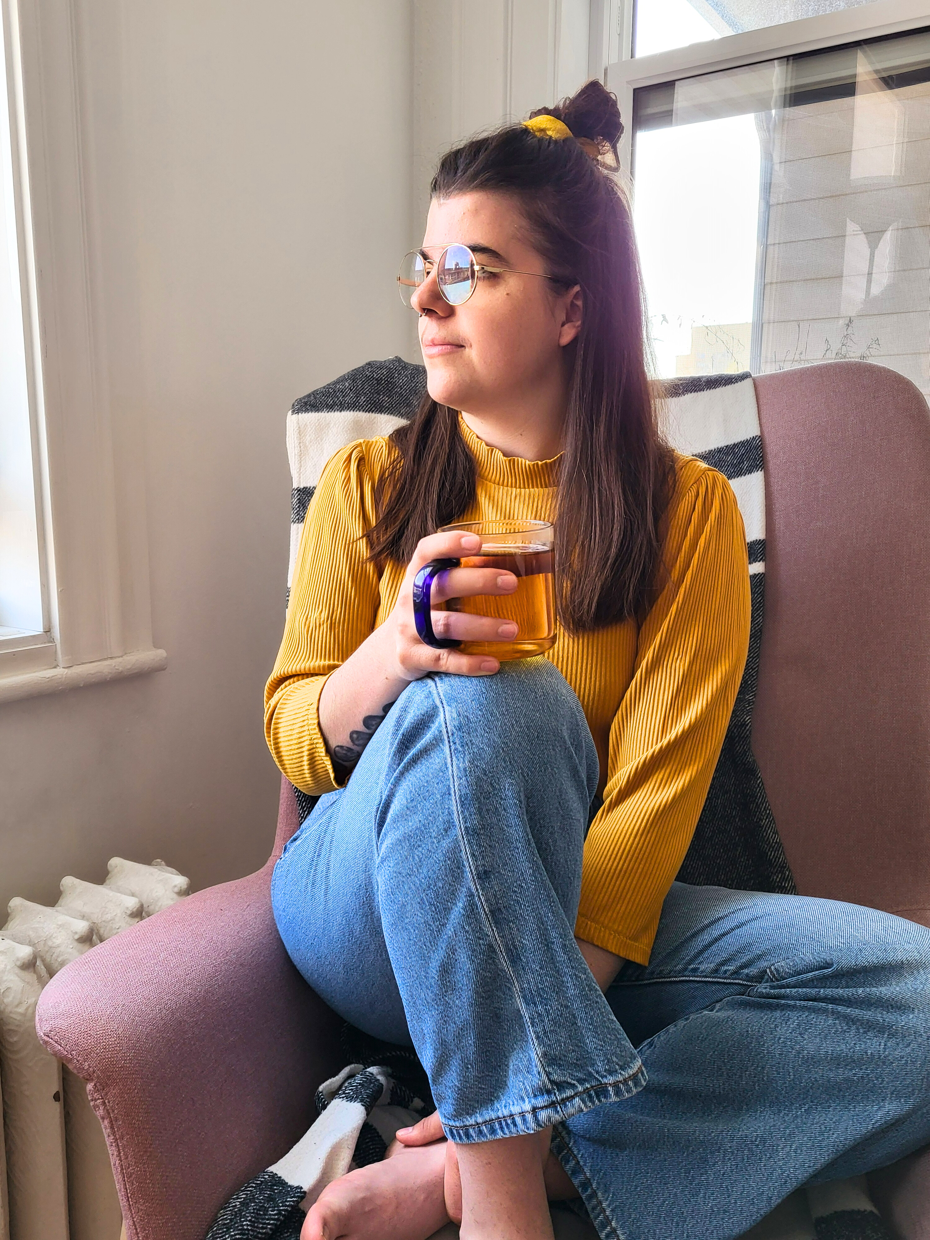 Catherine Perron, physiothérapeute, assise près d'une fenêtre avec une tasse de thé