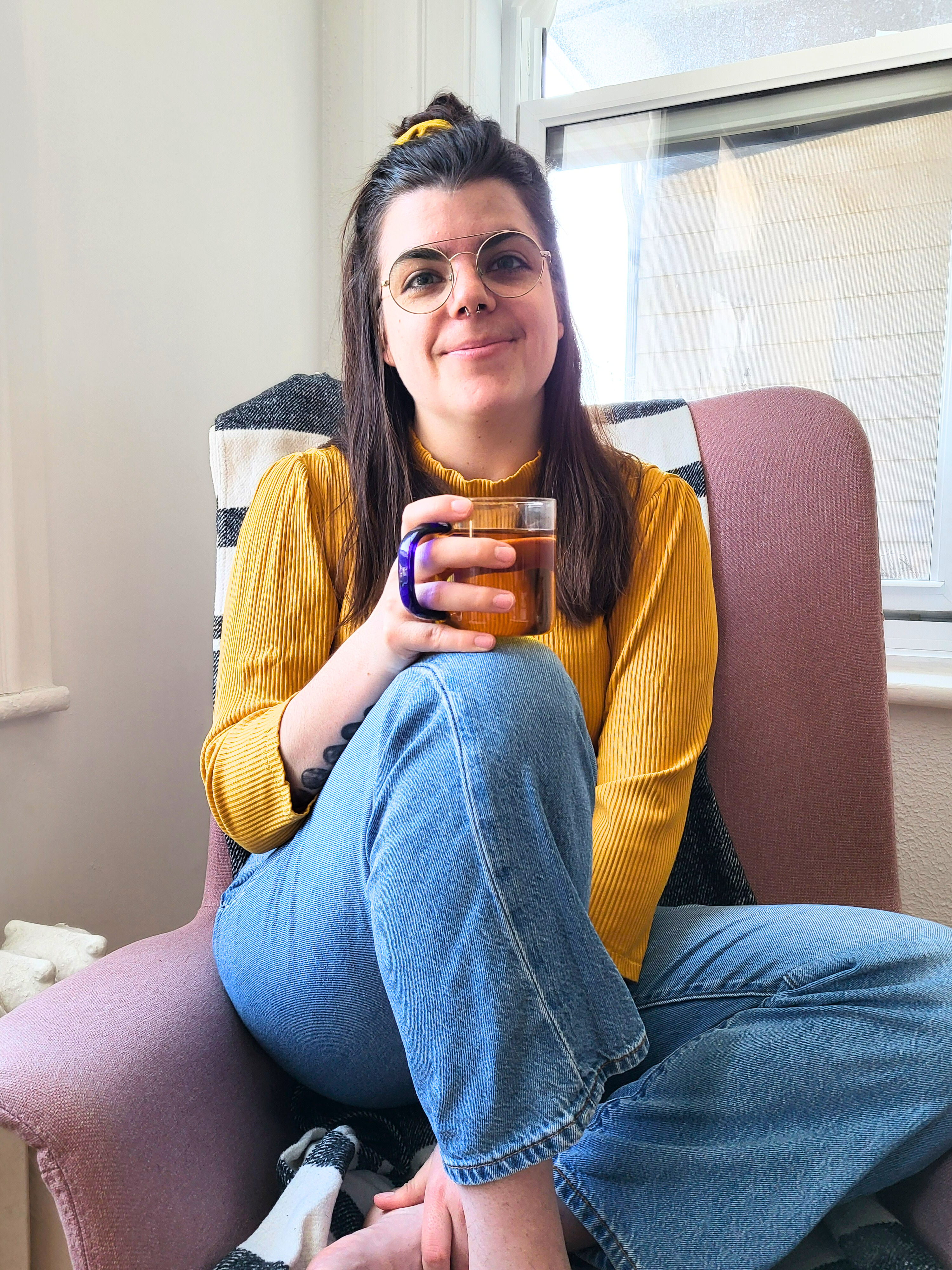 Catherine Perron, physiothérapeute, assise avec une tasse de thé face à la caméra
