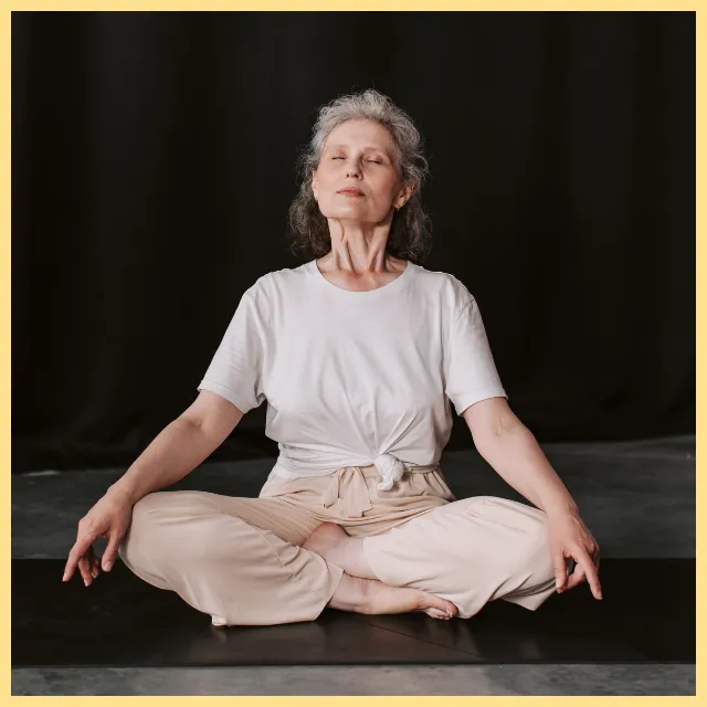 Femme sereine, assise en tailleur au sol, les yeux fermés