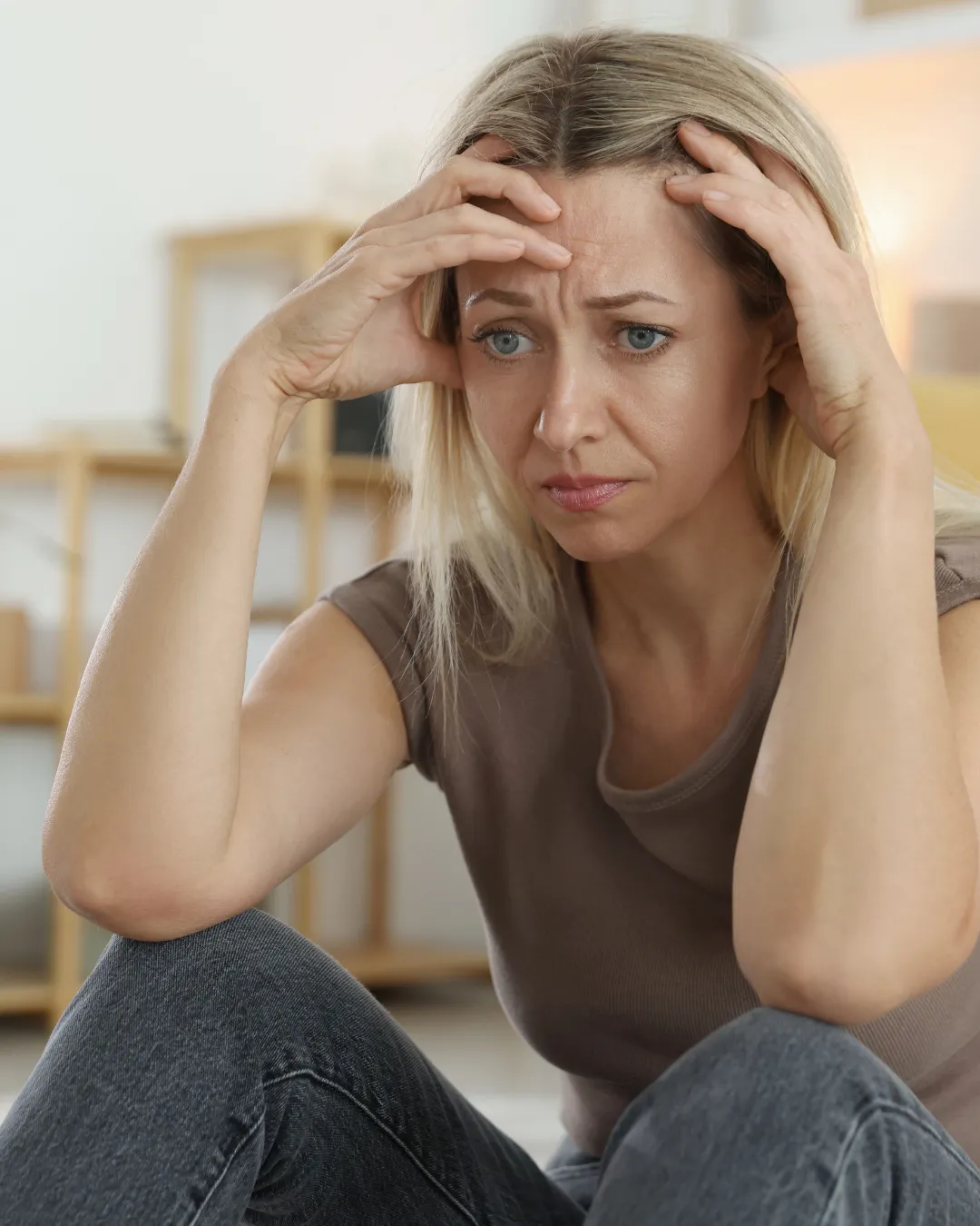 Femme découragée, assise avec la tête dans les mains