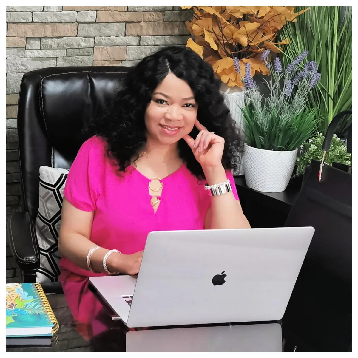 Nathlie Noumen of The Extensionista Academy & Salon sitting at a desk with a laptop open