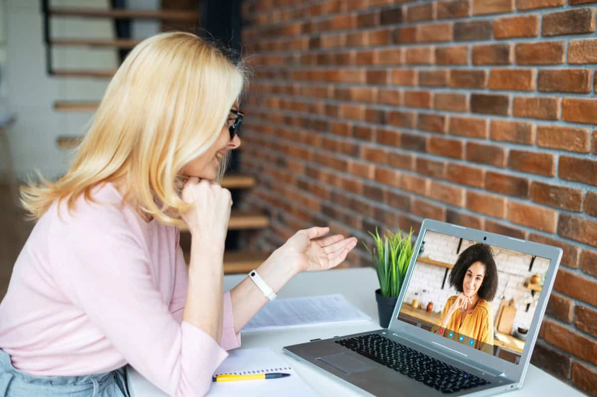 A woman is sitting at a desk with a laptop and a camera on it.