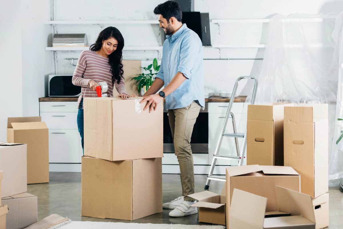 Cheerful-latin-couple-packing-boxes-while-moving-to-new-home
