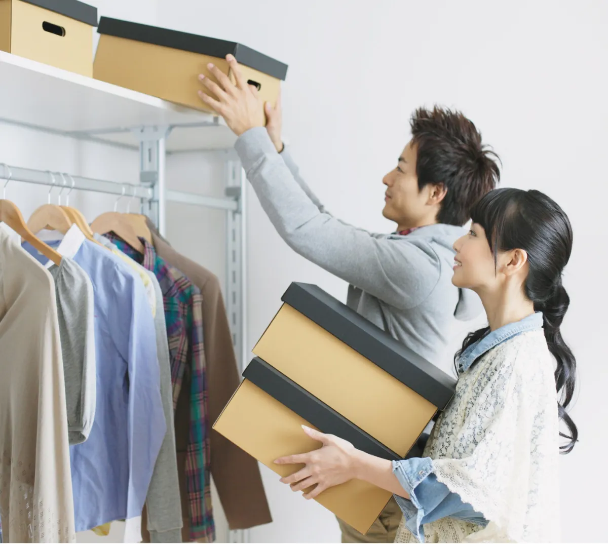 A man and woman are organizing boxes in a closet, both focused on their task.