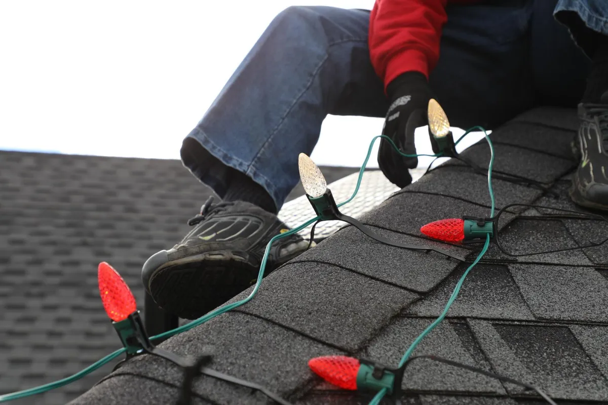A member of AG Holiday Lighting installing christmas lights on a roof