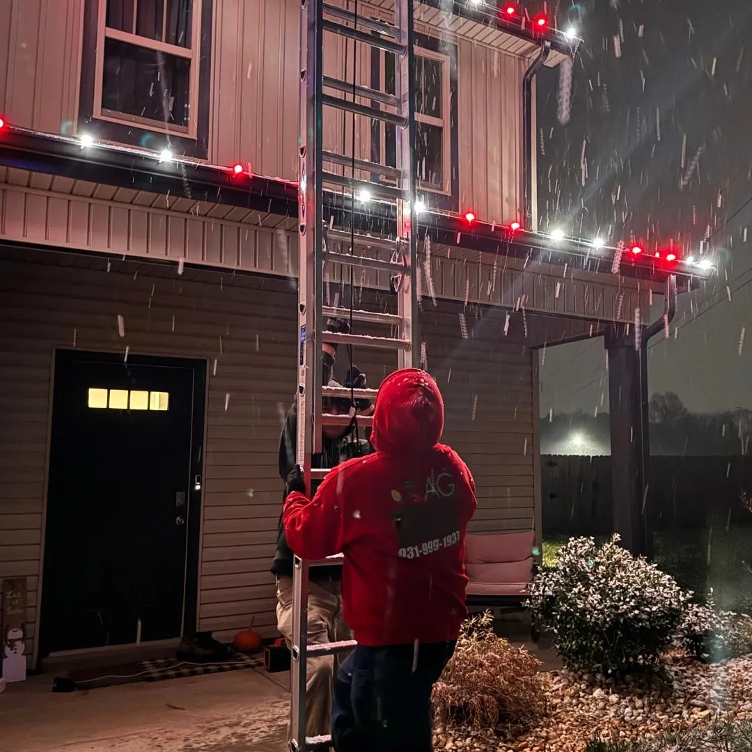 one of AG Holiday Lighting's technicians installing lights in the winter snow