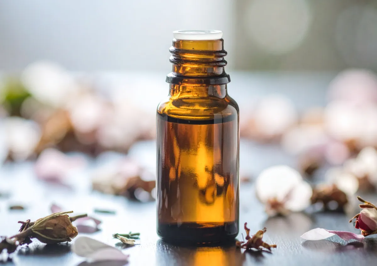 ESSENTIAL OIL BOTTLE WITH PETALS SURROUNDING IT