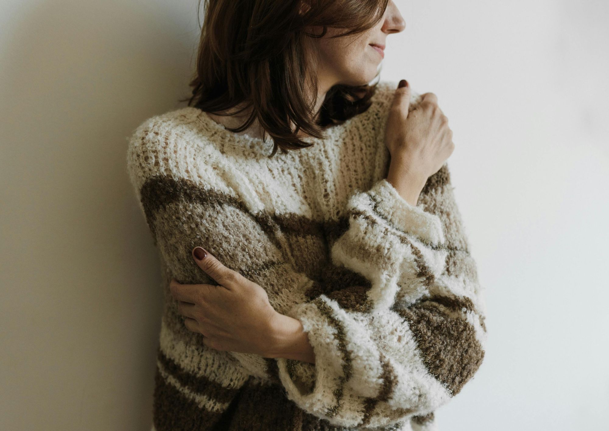 woman wearing cosy jumper hugging herself in self care feeling hormonal or menopausal symptoms